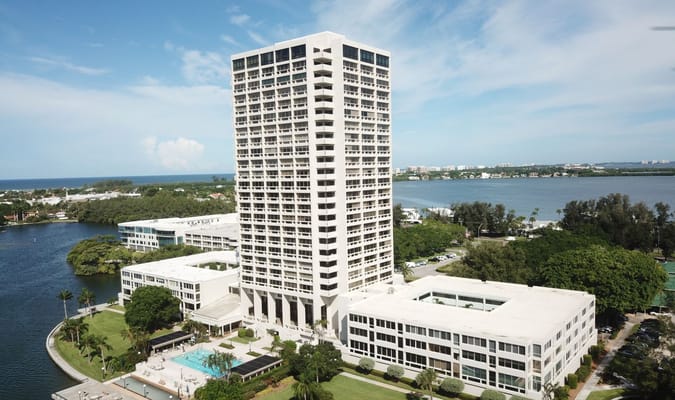Aerial view of Plymouth Harbor, showcasing tall buildings and lush surroundings near Sarasota Bay.
