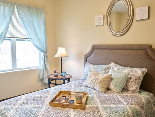 Comfortable bedroom with blue curtains and decorative pillows.