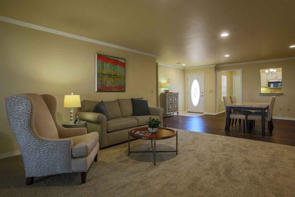 A spacious living room with a sofa, armchair, and dining area.