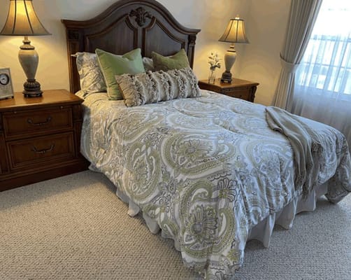 Comfortable bedroom featuring a bed with patterned bedding and wooden furniture