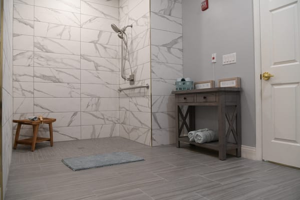 Clean and modern shower area with a wooden stool and towels