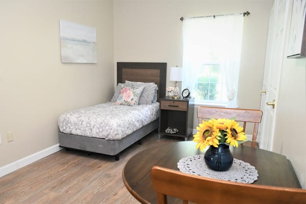 Brightly lit room with single bed and dining table