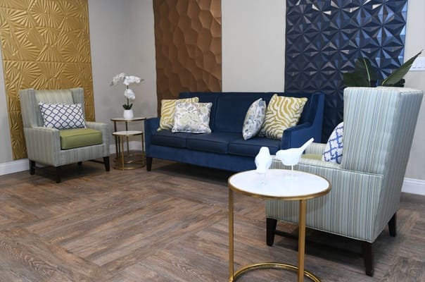 Lounge area featuring a blue sofa, patterned chairs, and decorative walls