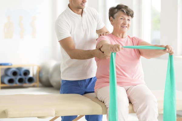 Elderly woman participating in a stretching exercise with staff help