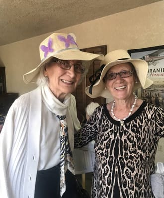 Two smiling residents wearing hats in a common area