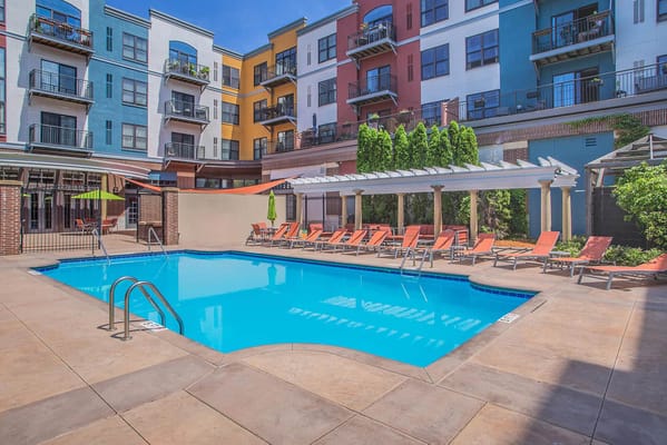 Pool area with sun loungers and colorful apartment building