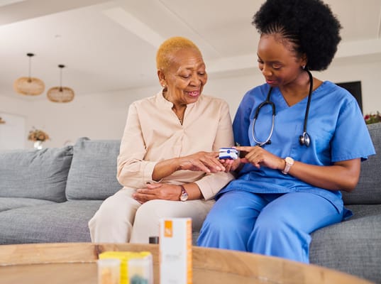 Nurse showing health device to a senior resident in a common area