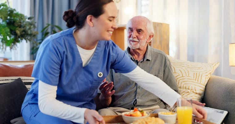 Staff member serving food to a resident in a cozy setting