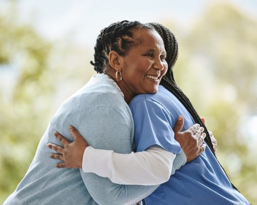A caregiver and resident sharing a warm hug