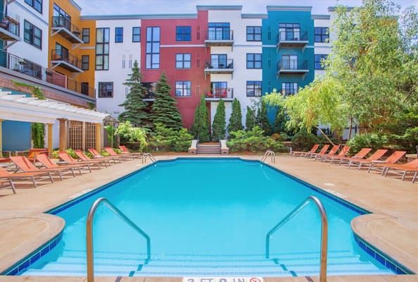 Outdoor pool area with lounge chairs and colorful building in background