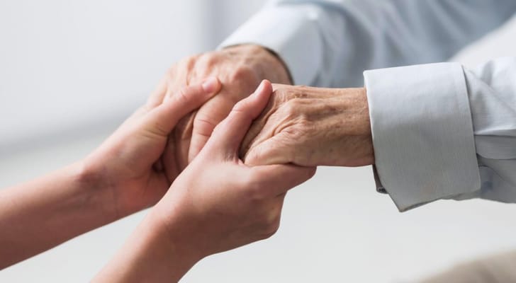 An elderly hand gently holding a younger hand
