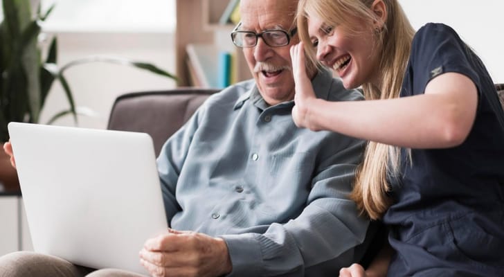 A caregiver and senior happily interacting with a laptop
