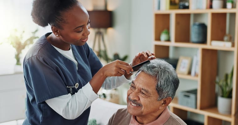 A caregiver styling hair of a smiling senior resident