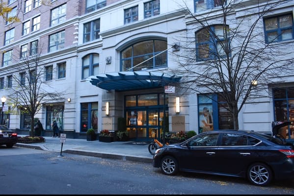 Building entrance with blue awning and parked car