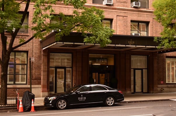 Building entrance with a parked vehicle and greenery