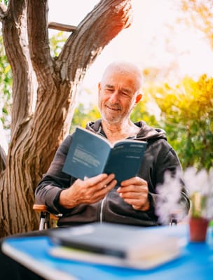 Senior resident reading a book outdoors