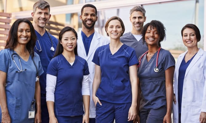A group of healthcare staff in scrubs posing outdoors