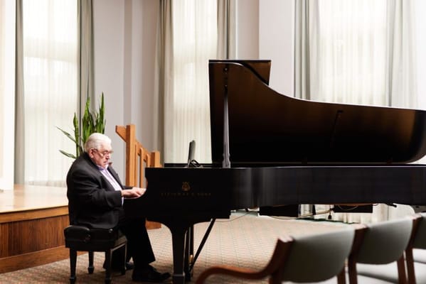 Resident playing piano in a light-filled common area