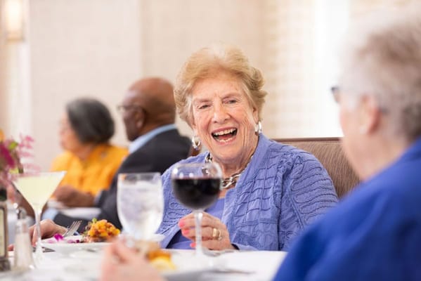 Residents enjoying a meal and conversation in a dining room