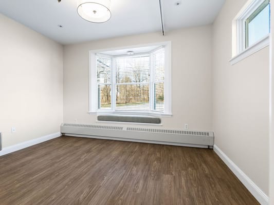 An empty interior room with large windows and wooden flooring