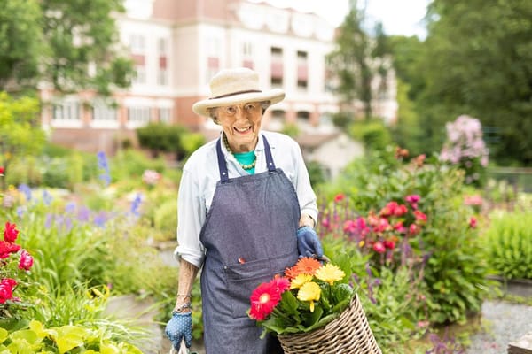 Elderly woman gardening with colorful flowers in a lush garden
