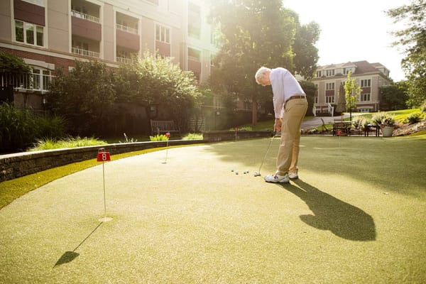 Resident practicing putting on a green outdoor area