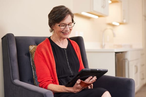 A resident enjoying time with a tablet in her room