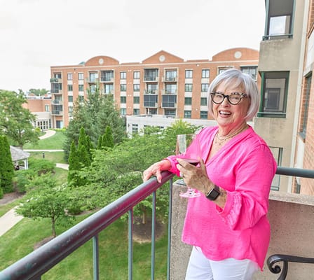 Resident enjoying a drink on a balcony with landscaped grounds