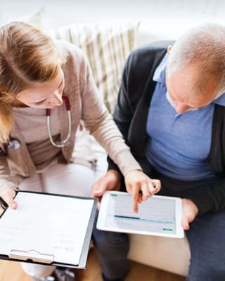 Healthcare worker assisting a senior with a tablet