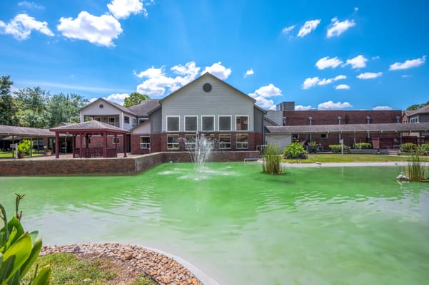 Exterior view of a senior living facility with a pond
