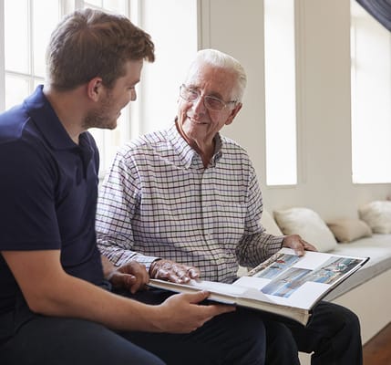 A caregiver and a resident sharing a photo album indoors