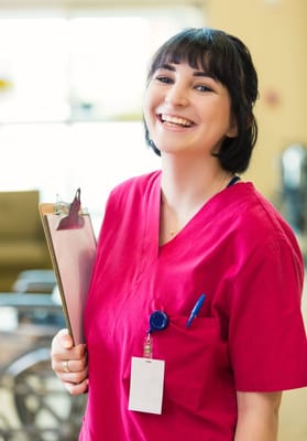 Nurse smiling while holding a clipboard in a facility