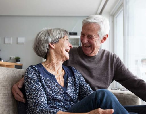 An elderly couple laughing together in a cozy setting