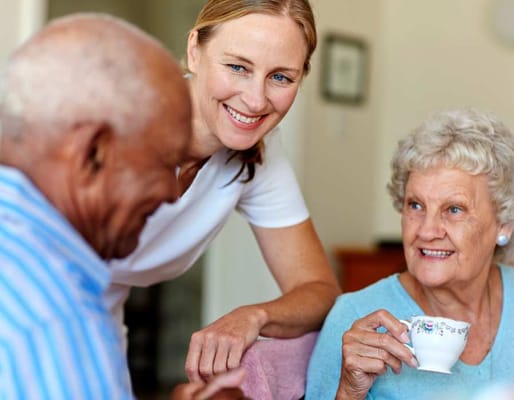 A staff member smiling with two senior residents
