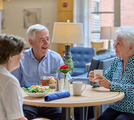 Three residents enjoying a meal together in a dining area
