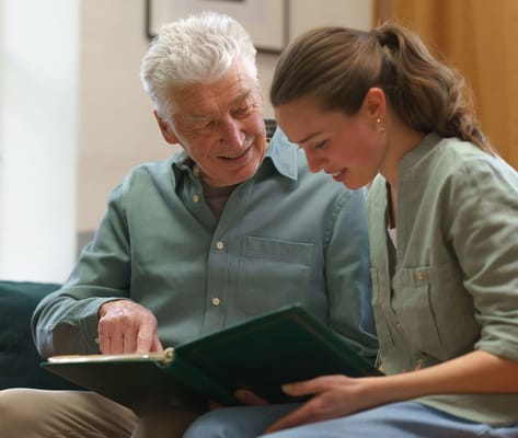 Senior resident looking through a photo album with staff