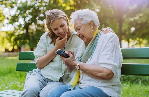 An elderly woman and caregiver sharing a moment outdoors