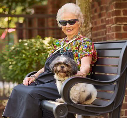 Senior resident smiling with a small dog in an outdoor space