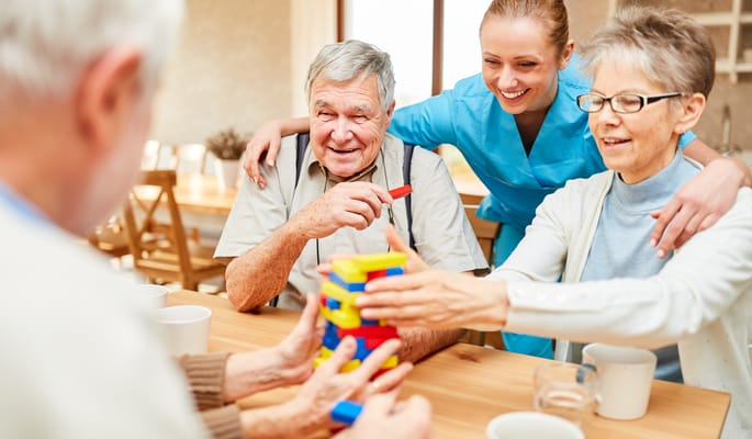 Residents and staff enjoying a play activity at a table