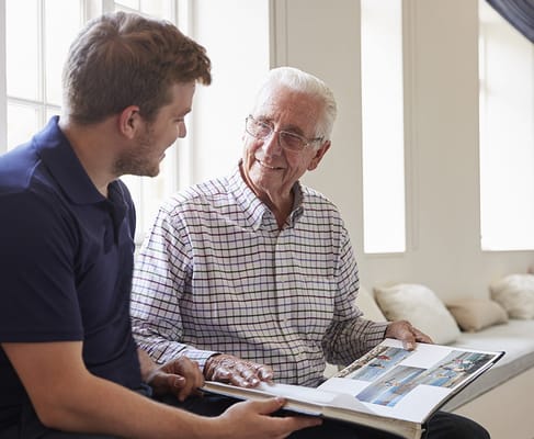 Senior resident looking at a photo album with staff member