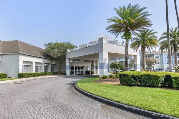 Exterior view of a senior living community entrance with palm trees