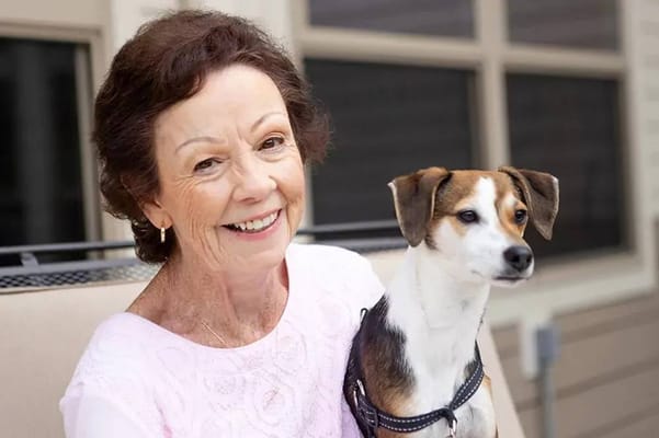 Senior resident smiling with a dog in an outdoor space