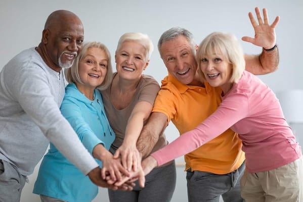 A group of joyful seniors with hands together in a circle