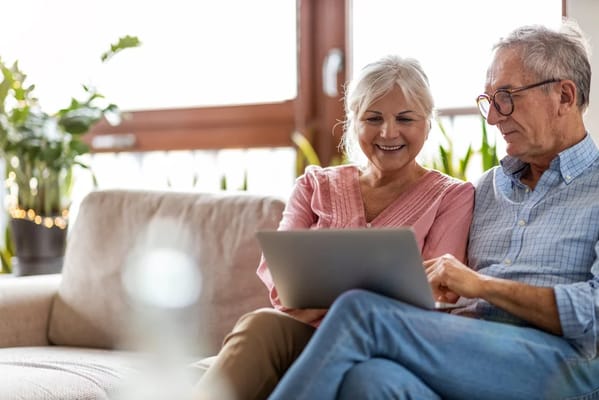 Seniors enjoying time together on a couch with a laptop