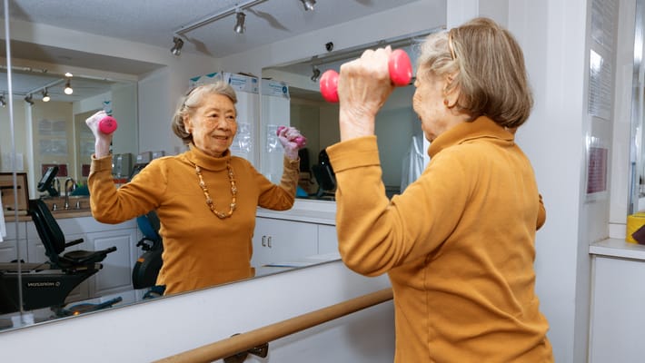 Senior resident exercising with dumbbells in an activity room