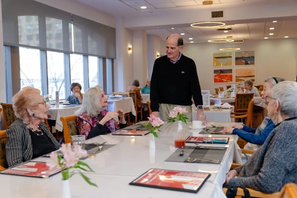 Residents dining and engaging with staff in the dining room
