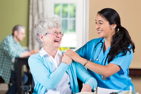 Nurse interacting with a smiling resident in a bright room