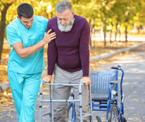 A caregiver assisting an elderly man with a walker outdoors