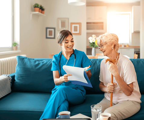 Caregiver assisting an elderly woman in a cozy living room
