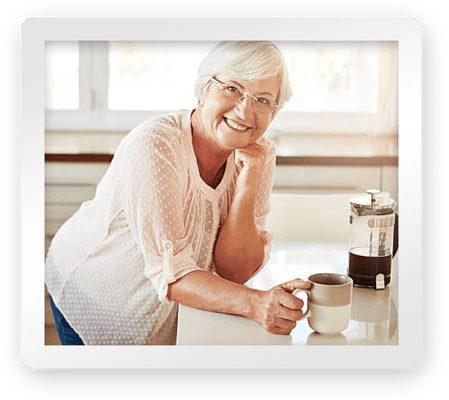 Smiling senior woman enjoying coffee in a bright kitchen